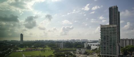 A high-rise building with a modern architectural design, surrounded by greenery and a river.