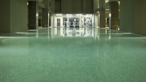 A large indoor swimming pool with clear water, surrounded by walls and pillars, and a reception area in the background. - V Hotel Lavender (Singapore)