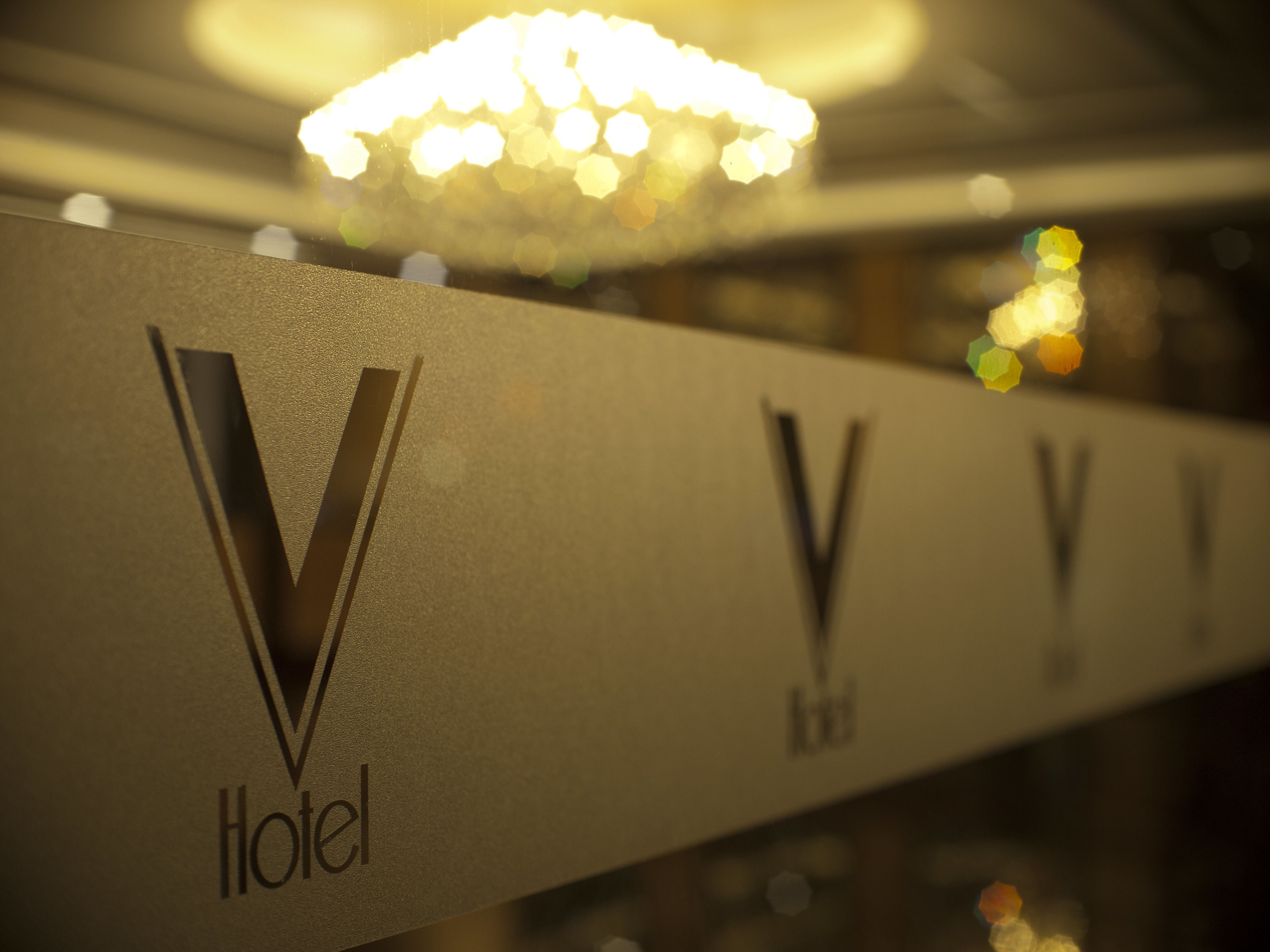 A hotel sign with a prominent 'V' logo and the word 'Hotel' beneath it.