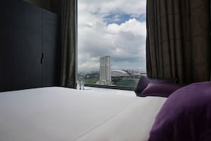 A hotel room with a bed, a window with curtains, and a view of a cityscape including a tall building and a bridge. - V Hotel Lavender (Singapore)