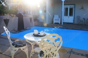 A pool area with a table and chairs, a door, and a wall with decorative elements. - Paradiso Guest House (Cape Town)