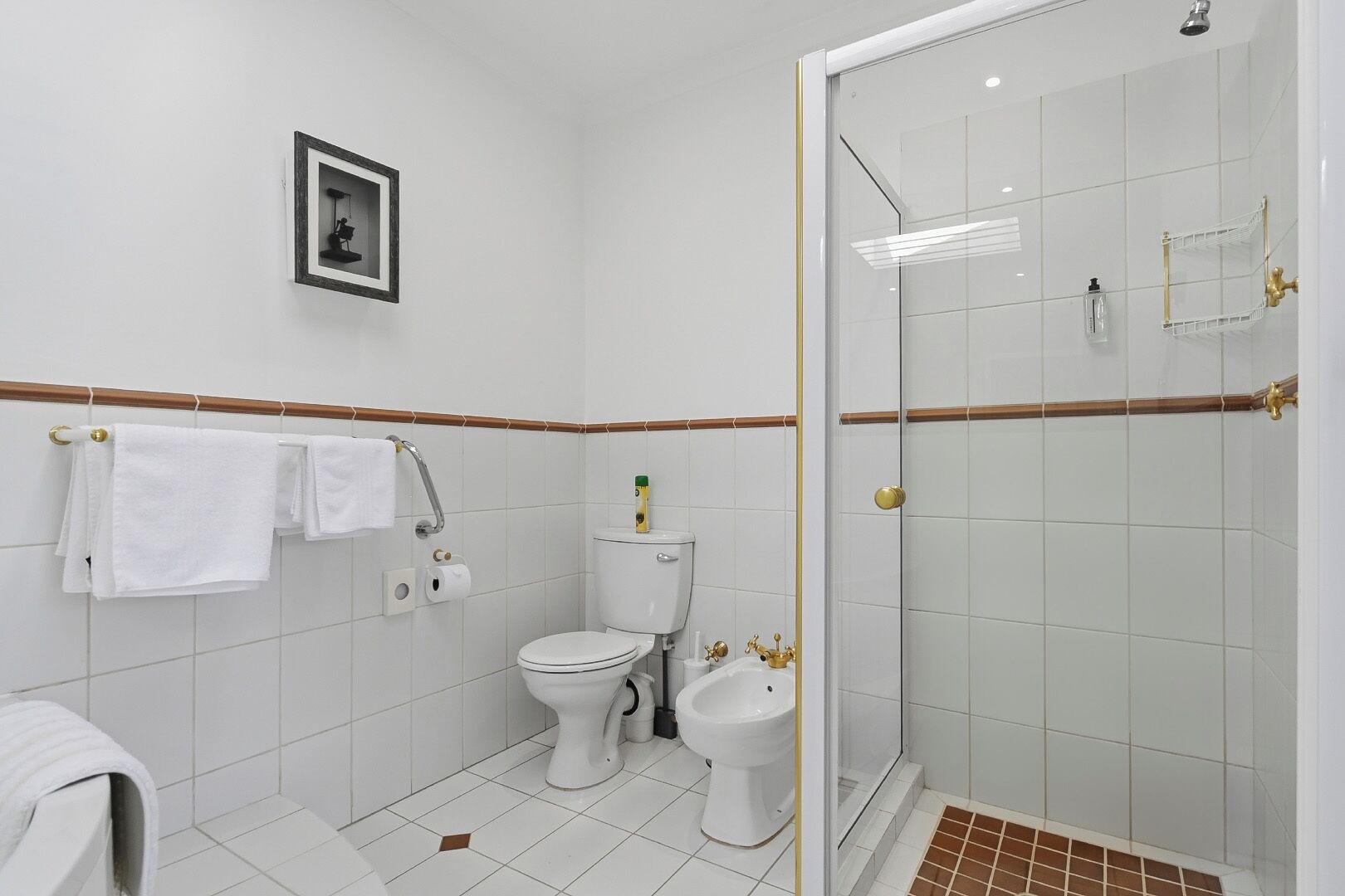 Une salle de bain comprenant des toilettes, un bidet et une douche séparée par une paroi en verre.