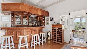 Un coin bar avec des meubles en bois, des tabourets et un meuble à bouteilles de vin.