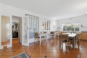 A spacious kitchen with a dining area, featuring a large window with a view of greenery. - Paradiso Guest House (Cape Town)
