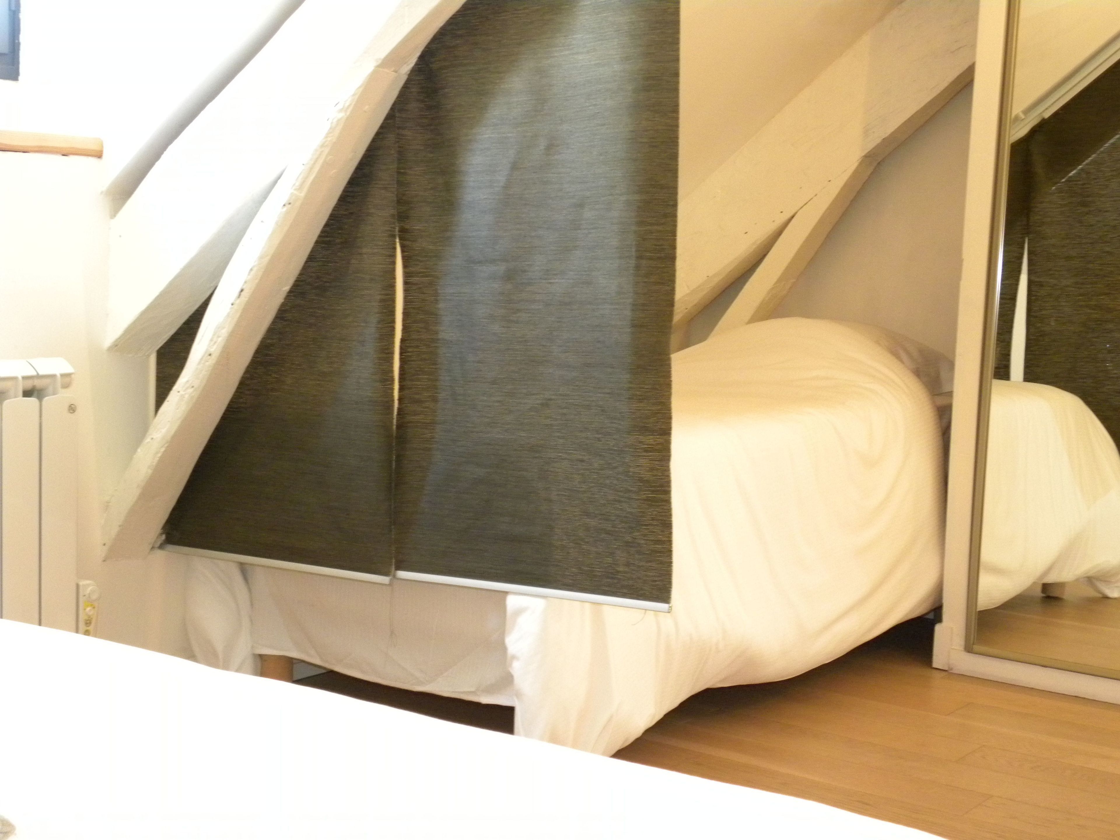 A bedroom with a bed, a window, and a mirror.