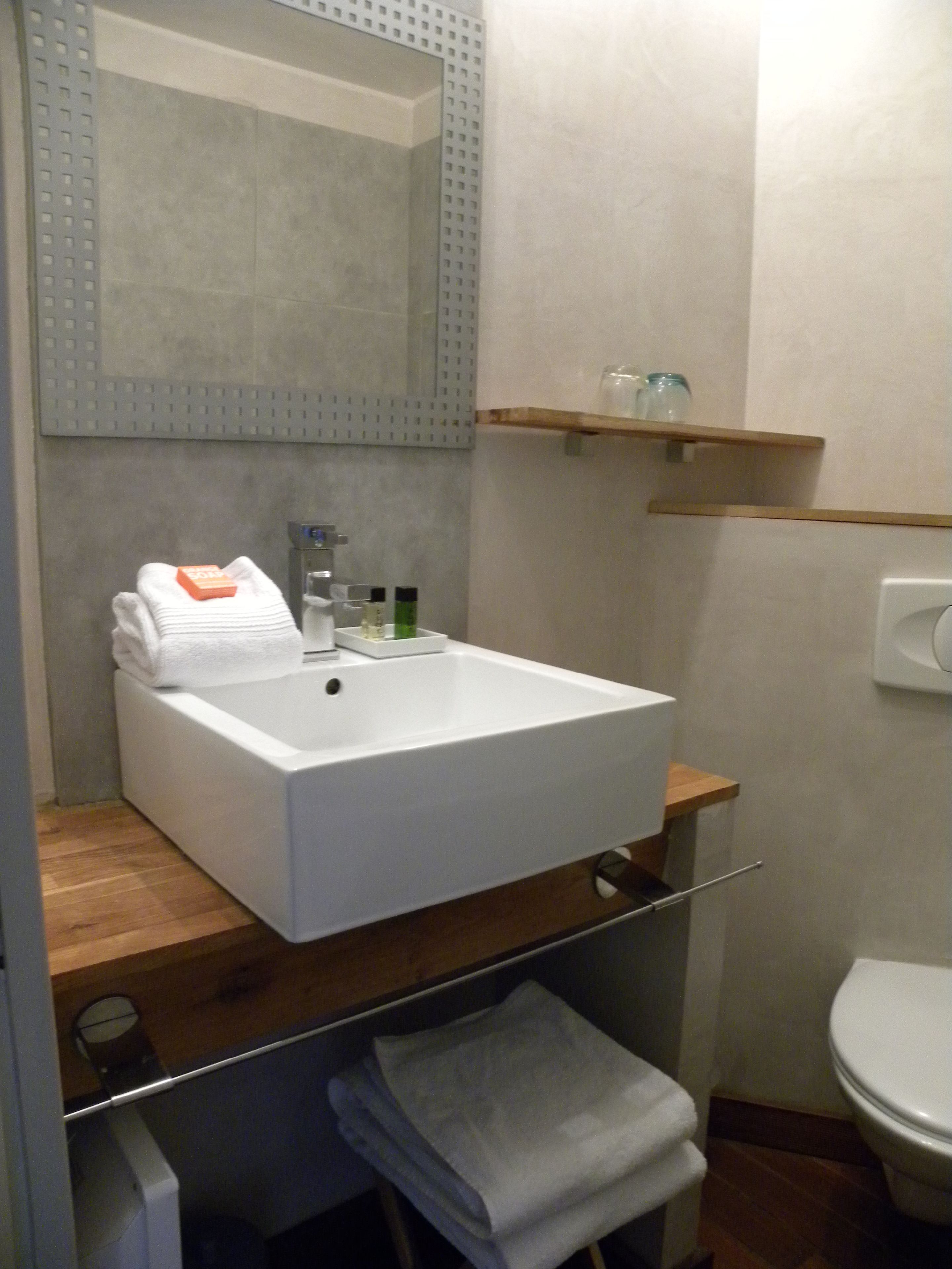 A bathroom with a white sink, mirror, and wooden shelves.