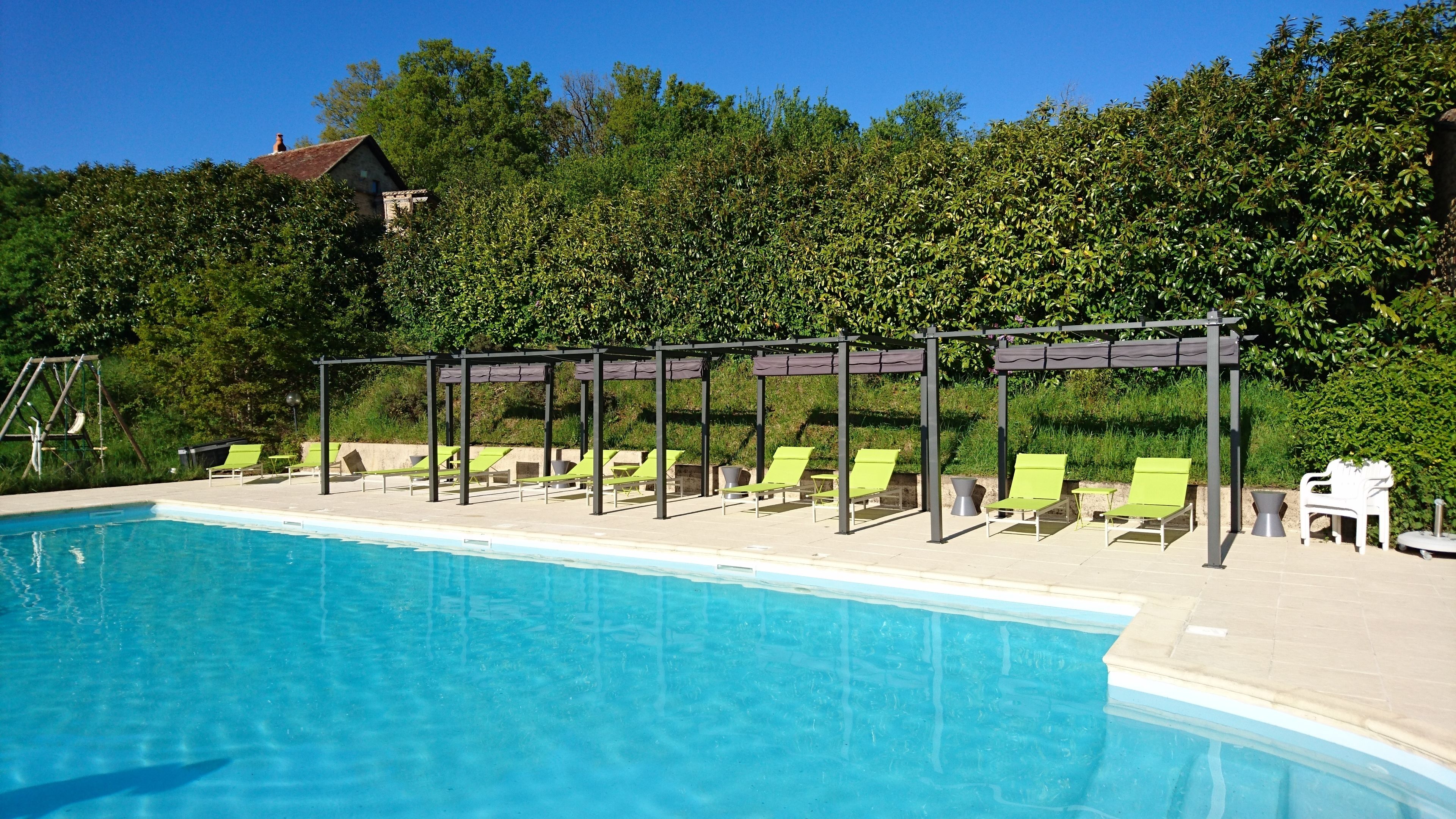 Una piscina con sillas de descanso verdes y una pérgola.