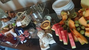 Une table de buffet proposant une variété d’aliments, notamment des fruits, des fromages et des condiments.