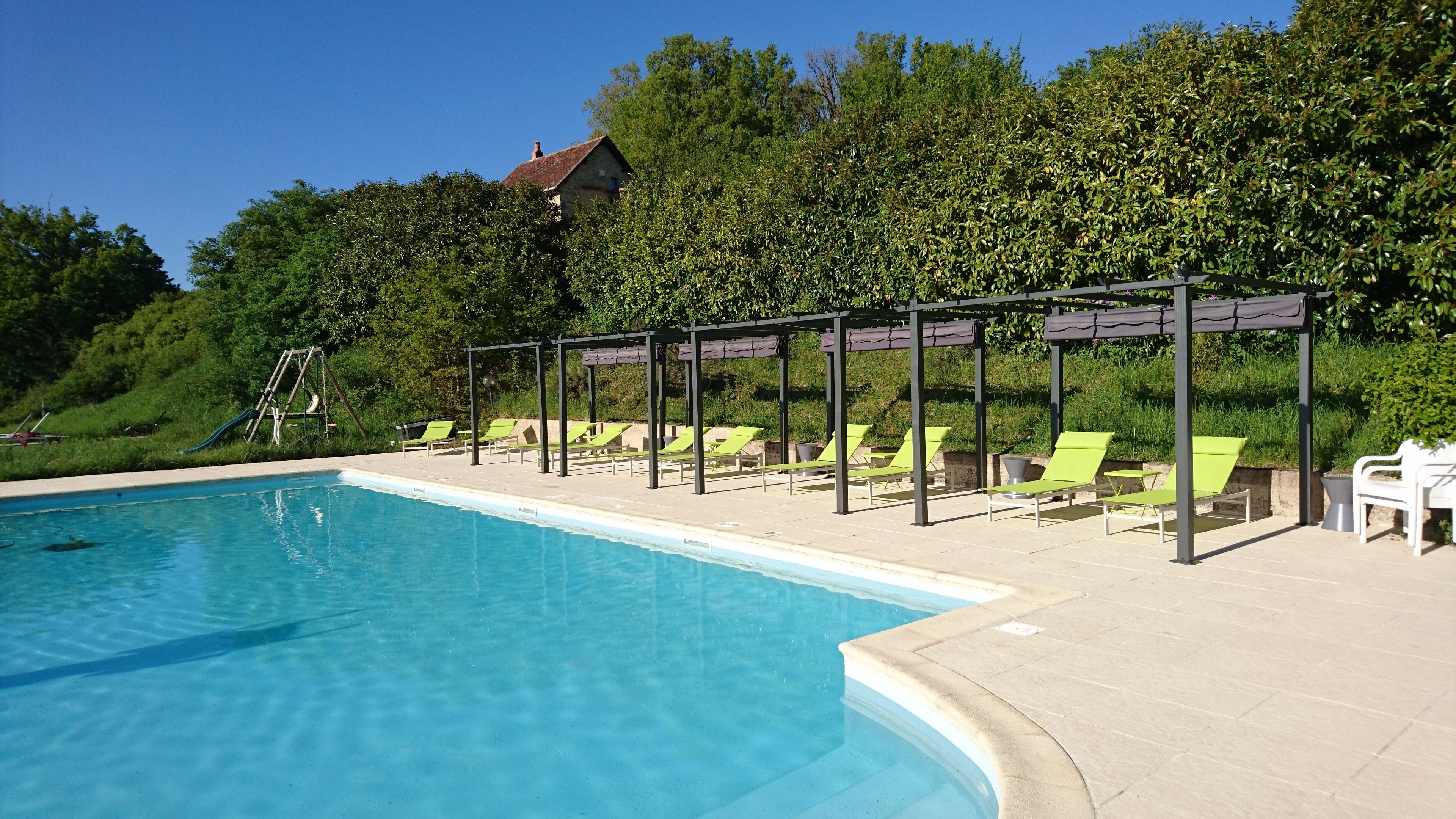 Una piscina con sillones de descanso y una pérgola.