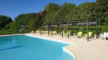 Una piscina con sillones de descanso y una pérgola.