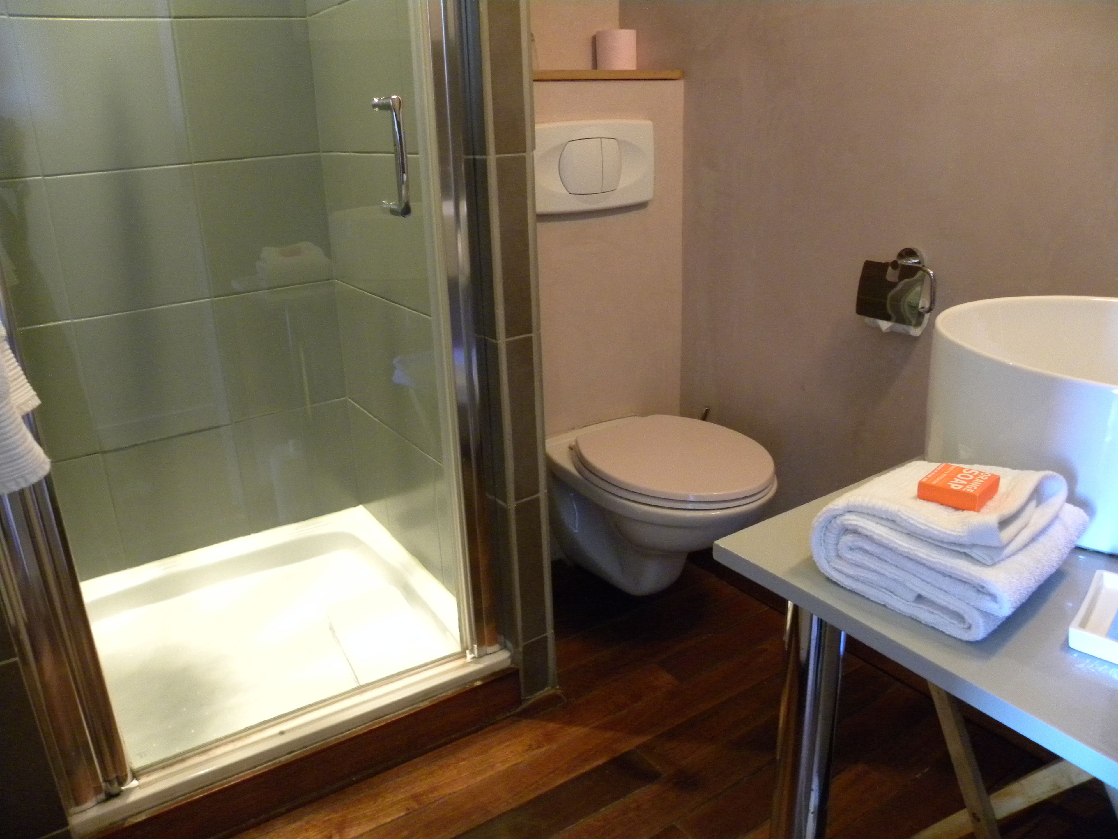 Bagno con doccia vetro, WC e lavabo con piletta di asciugamani.