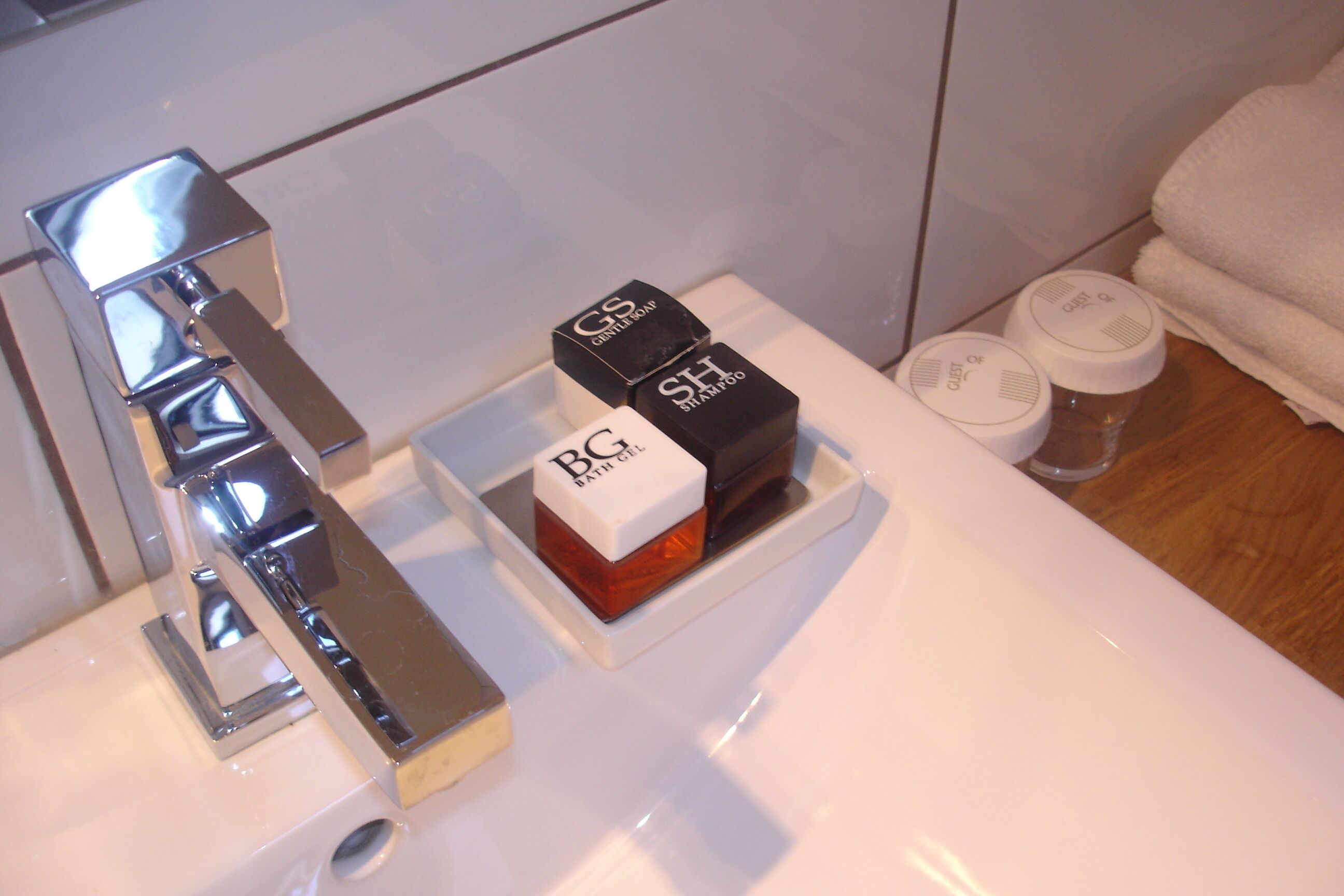 A bathroom with a chrome faucet, a white sink, and two boxes labeled "Bath & Body Works" on the counter.