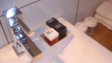 A bathroom with a chrome faucet, a white sink, and two boxes labeled "Bath & Body Works" on the counter.
