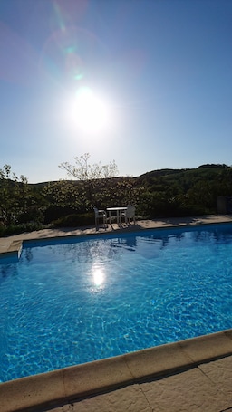 Una piscina al aire libre de temporada, sombrillas