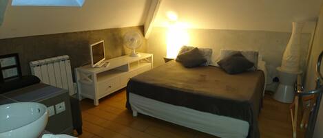 A bedroom with a bed, bedside table, lamp, and a skylight.