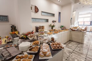 A buffet with various food items and utensils, a fish decoration on the wall, and a tiled floor. - Hotel Ariston (Varazze)