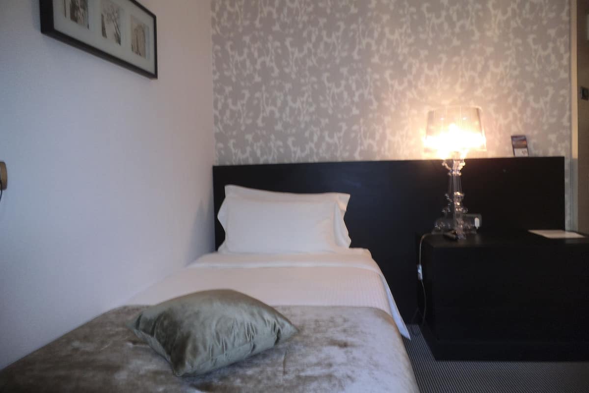 Ein Hotelzimmer mit einem Bett, einem Nachttisch und einer Lampe.