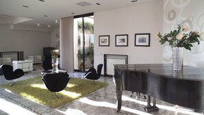 A modern living room with a piano, a fireplace, and a large window. - Hotel Ariston (Varazze)