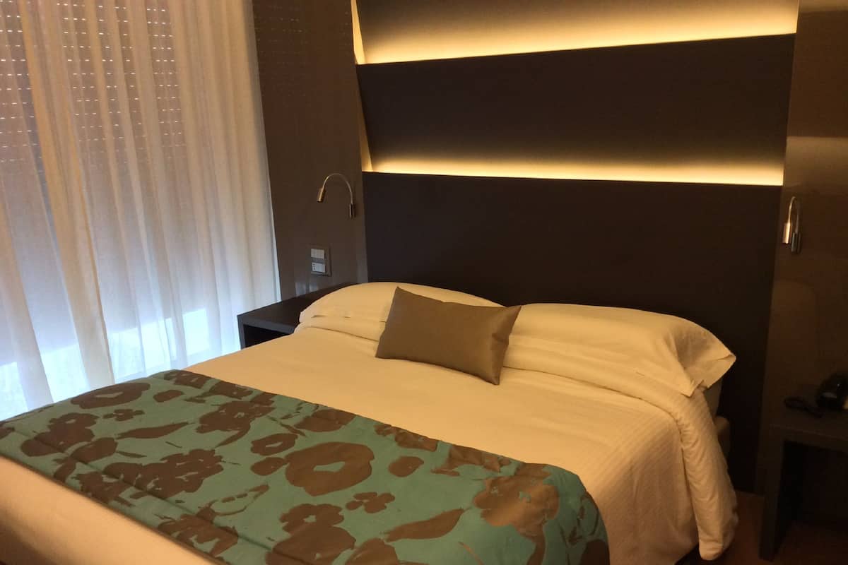 Ein Hotelzimmer mit einem Bett, einem Nachttisch und einer Wandleuchte.