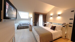 A modern hotel room with a large bed, a sofa, a TV mounted on the wall, and a window with curtains. - Hotel Ariston (Varazze)