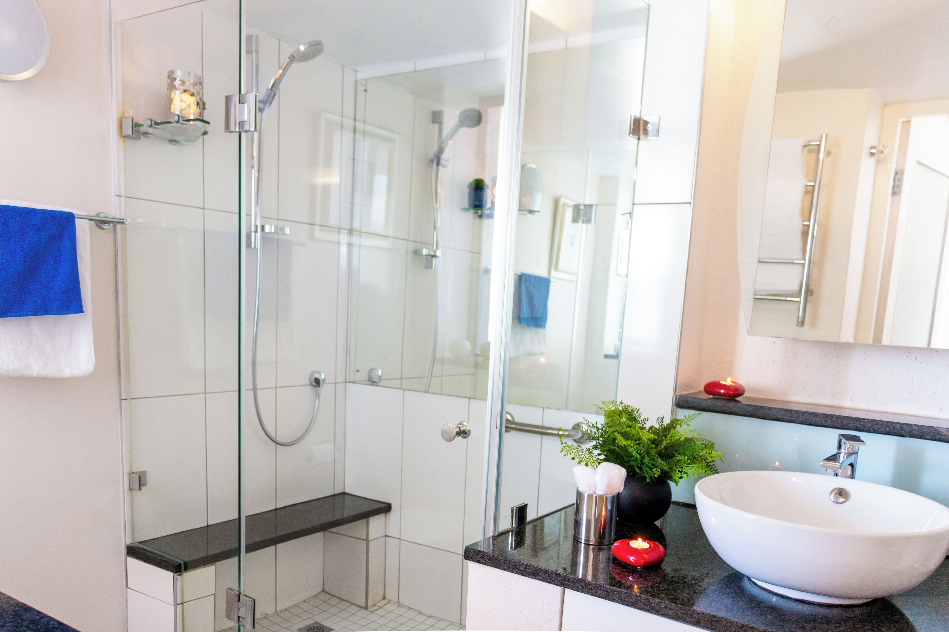 A modern bathroom with a glass-enclosed shower, a white sink, and a large mirror.