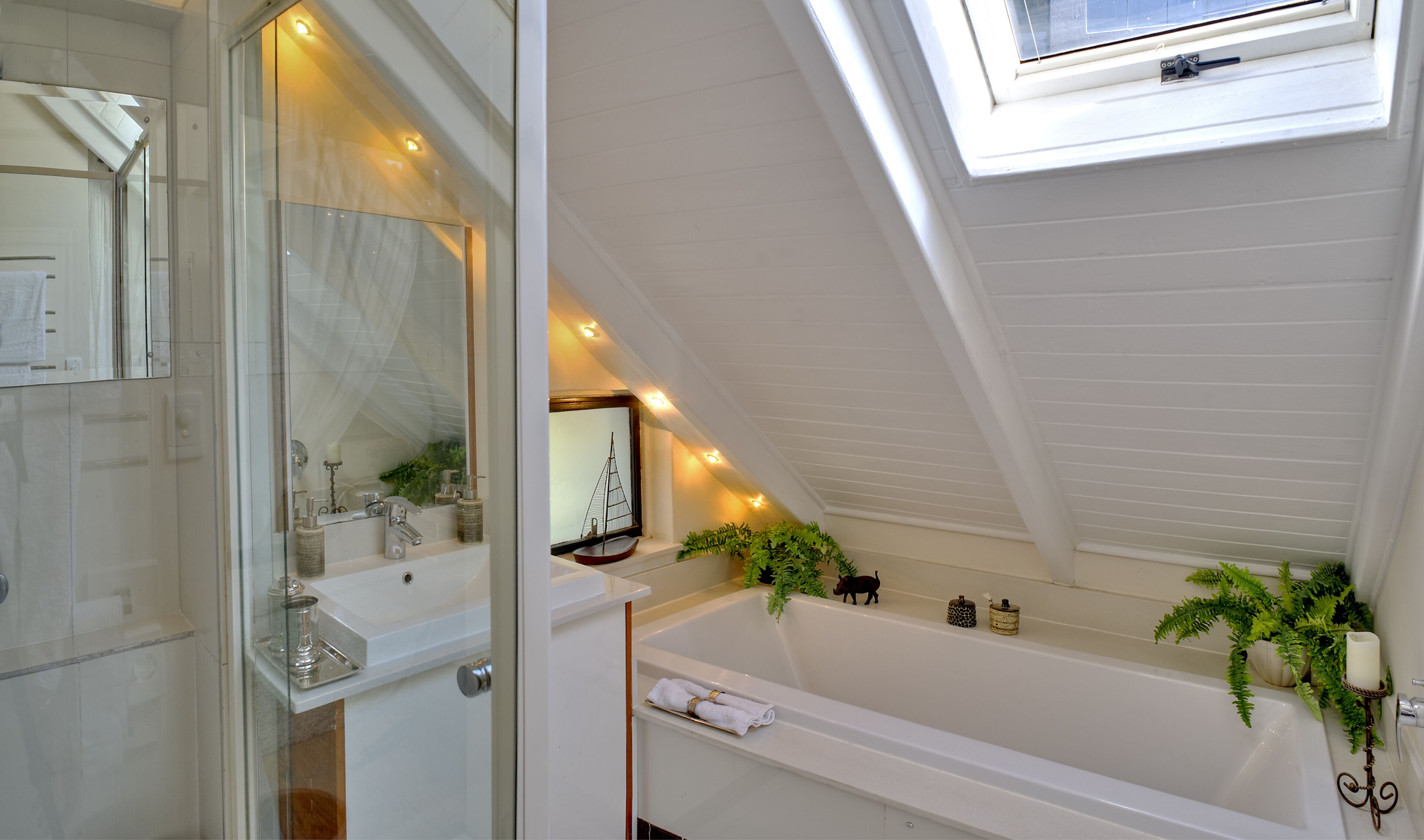 A modern bathroom with a skylight, a bathtub, and a vanity with a mirror.