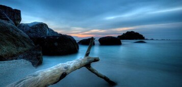 A beach with large rocks and a driftwood log.
