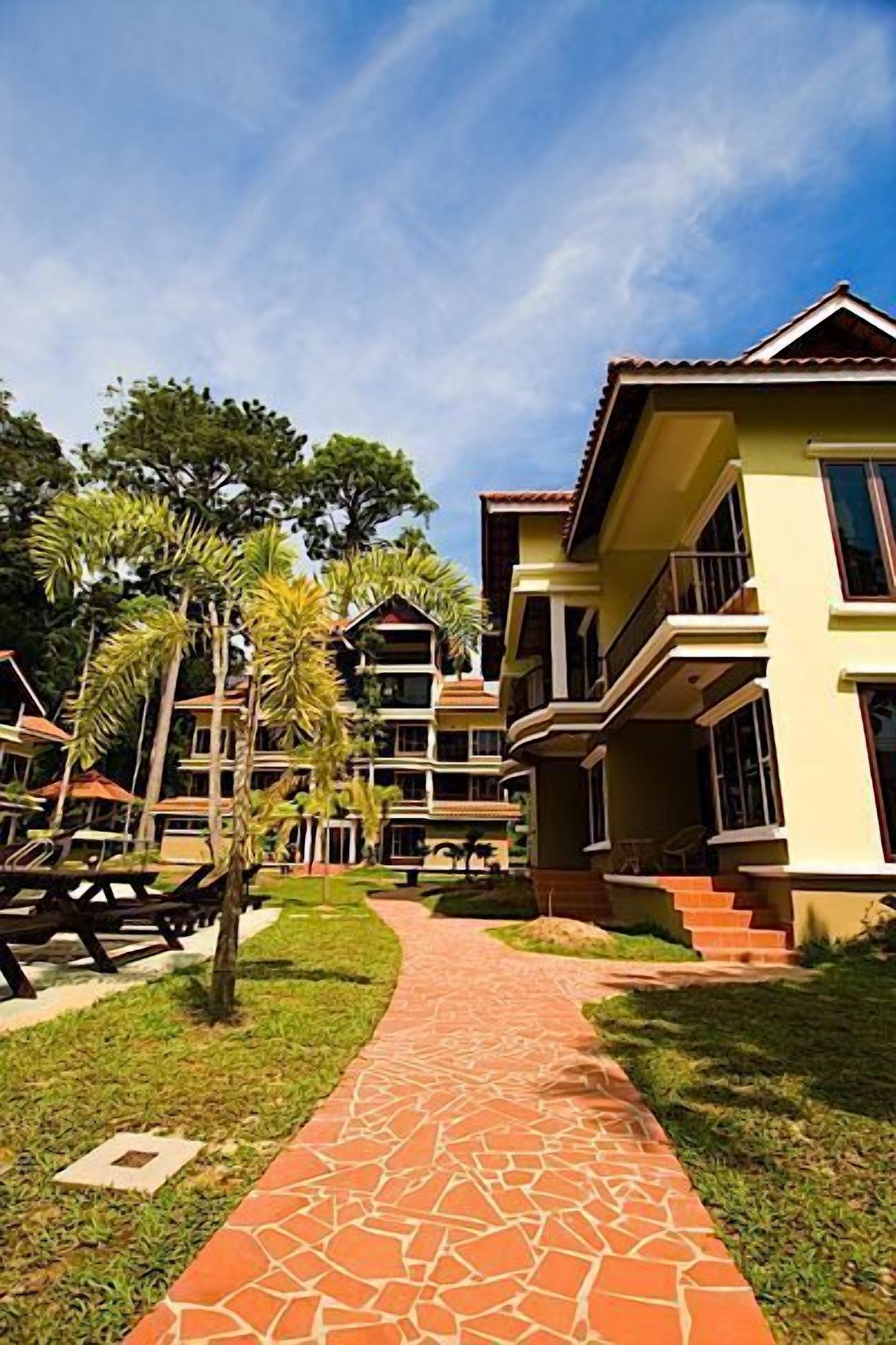 Un resort con edificios de varios pisos, un camino pavimentado y palmeras.