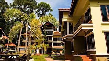 Un resort con edificios de varios pisos, un camino pavimentado y palmeras.