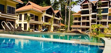 A resort with a swimming pool, multiple balconies, and a tropical setting.