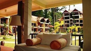 A hotel room with a bed, a lamp, and a view of other hotel buildings and greenery. - Anjungan Beach Resort (Pangkor Island)