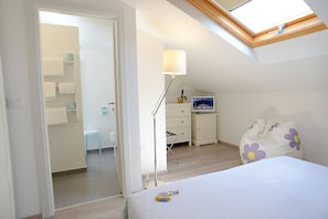 Cozy retreat with a skylight above the bed, a comfortable bed, and a bedside table with a lamp.