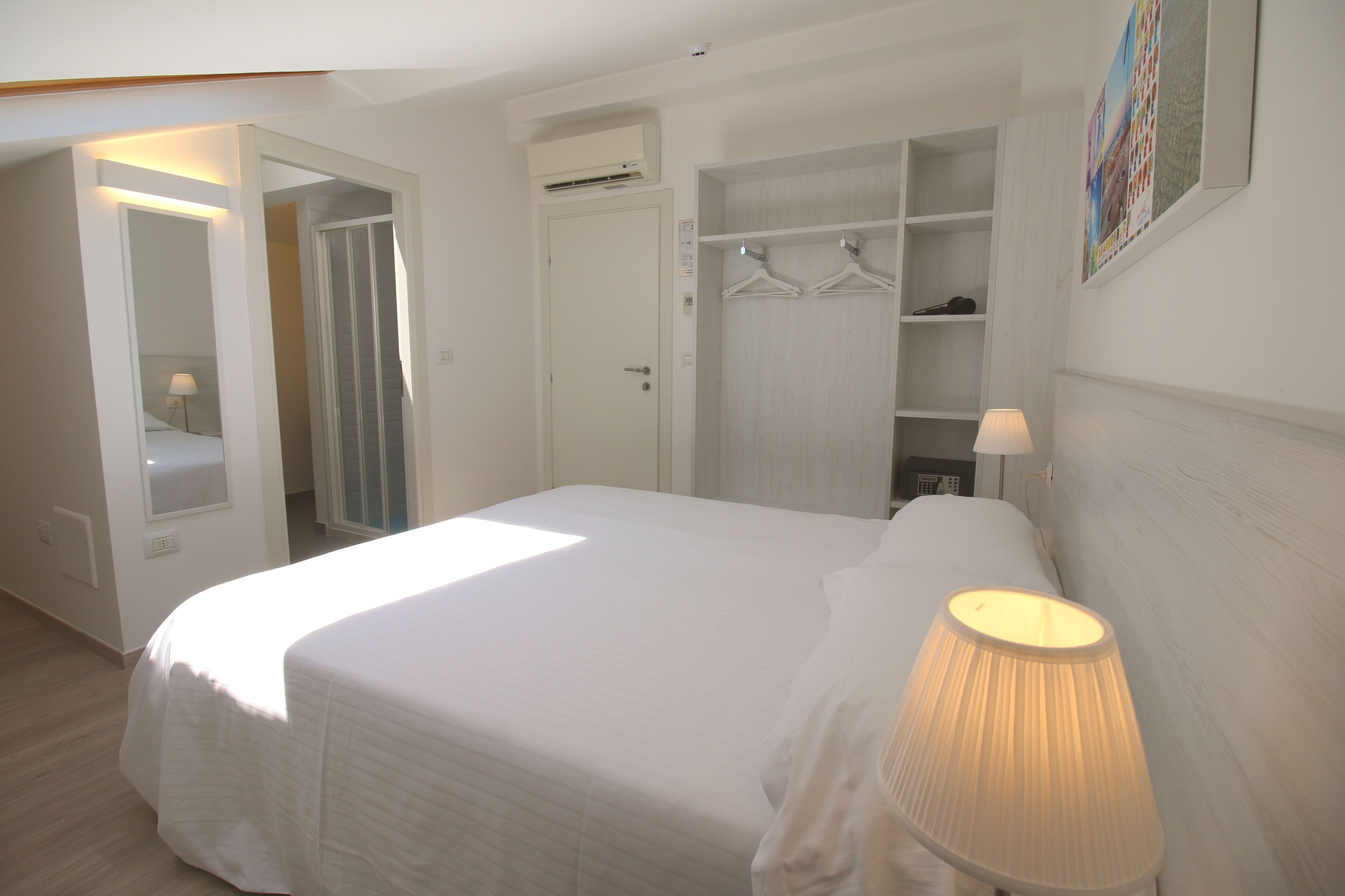 A bedroom with a bed, a bedside lamp, a wardrobe, and a mirror.