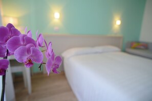 A bedroom with a bed, a nightstand, and a wall-mounted lamp. - Maree Hotel (Cesenatico)