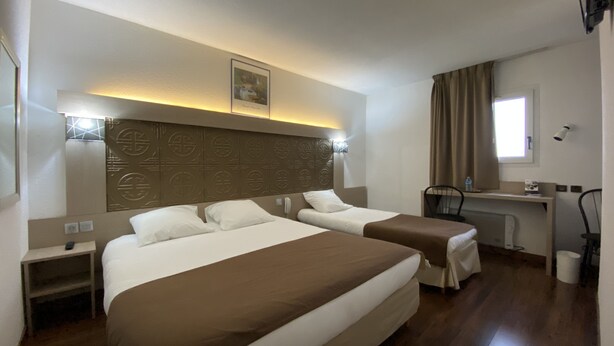 A hotel room with two beds, a desk, a chair, and a window with curtains. - Hotel Kimotel (Epone)