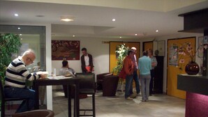 A hotel lobby with a dining area, a reception desk, and a large plant. - Hotel Kimotel (Epone)