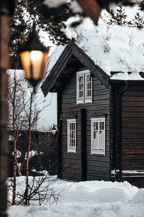 A wooden house with two windows and a garage door, surrounded by snow. - Bardøla Fjelltun (Hol)
