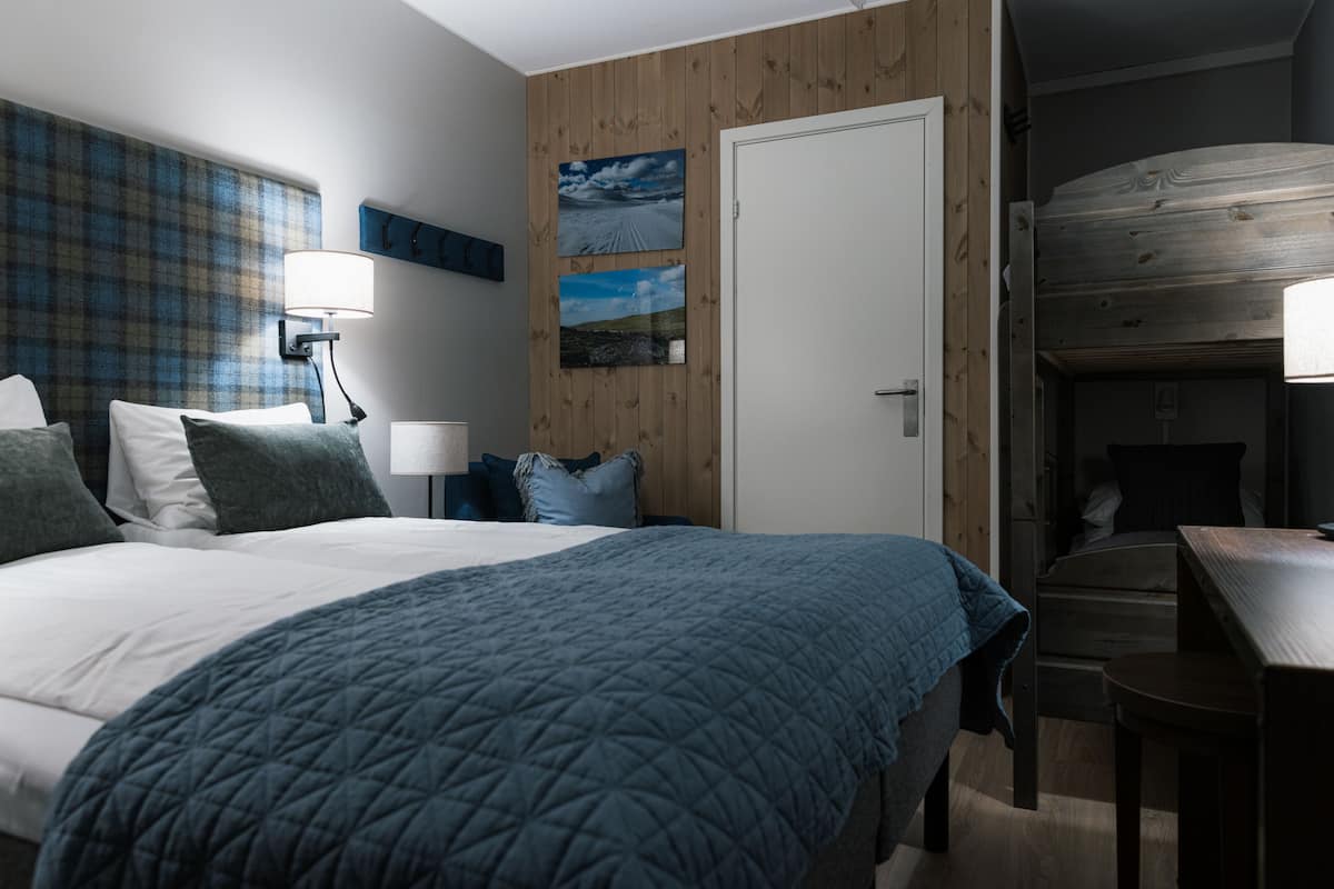 A bedroom with a large bed, a desk, and a bunk bed.