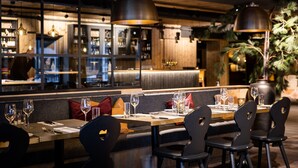 A restaurant with a long counter, black chairs, and pendant lighting. - Bardøla Fjelltun (Hol)