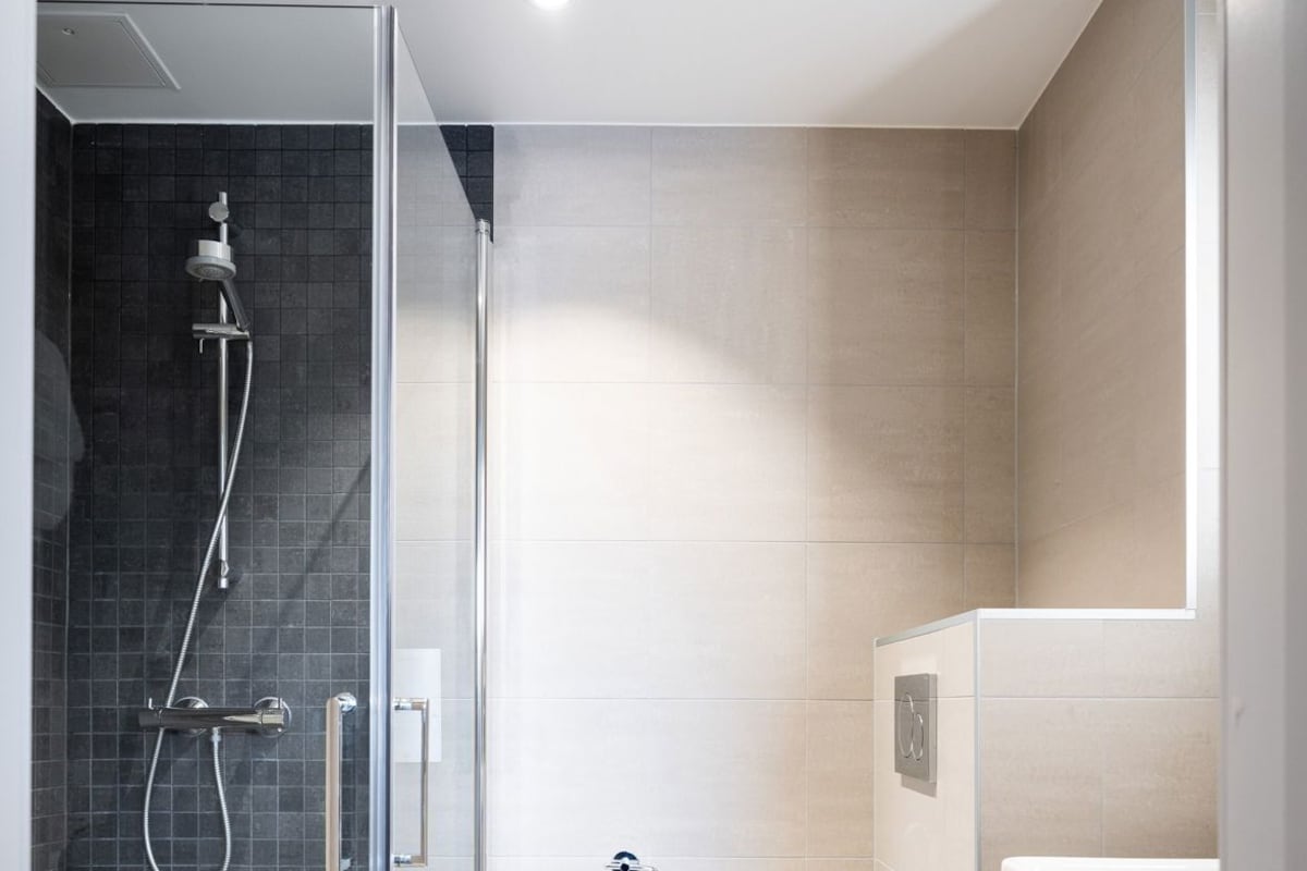 A modern bathroom with a glass-enclosed shower, a toilet, and a vanity with a mirror.