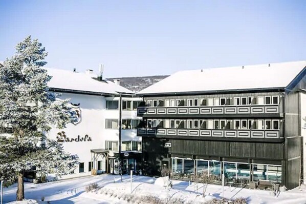 A multi-story building with a snow-covered roof and a sign that reads "Bardels." - Bardøla Fjelltun (Hol)