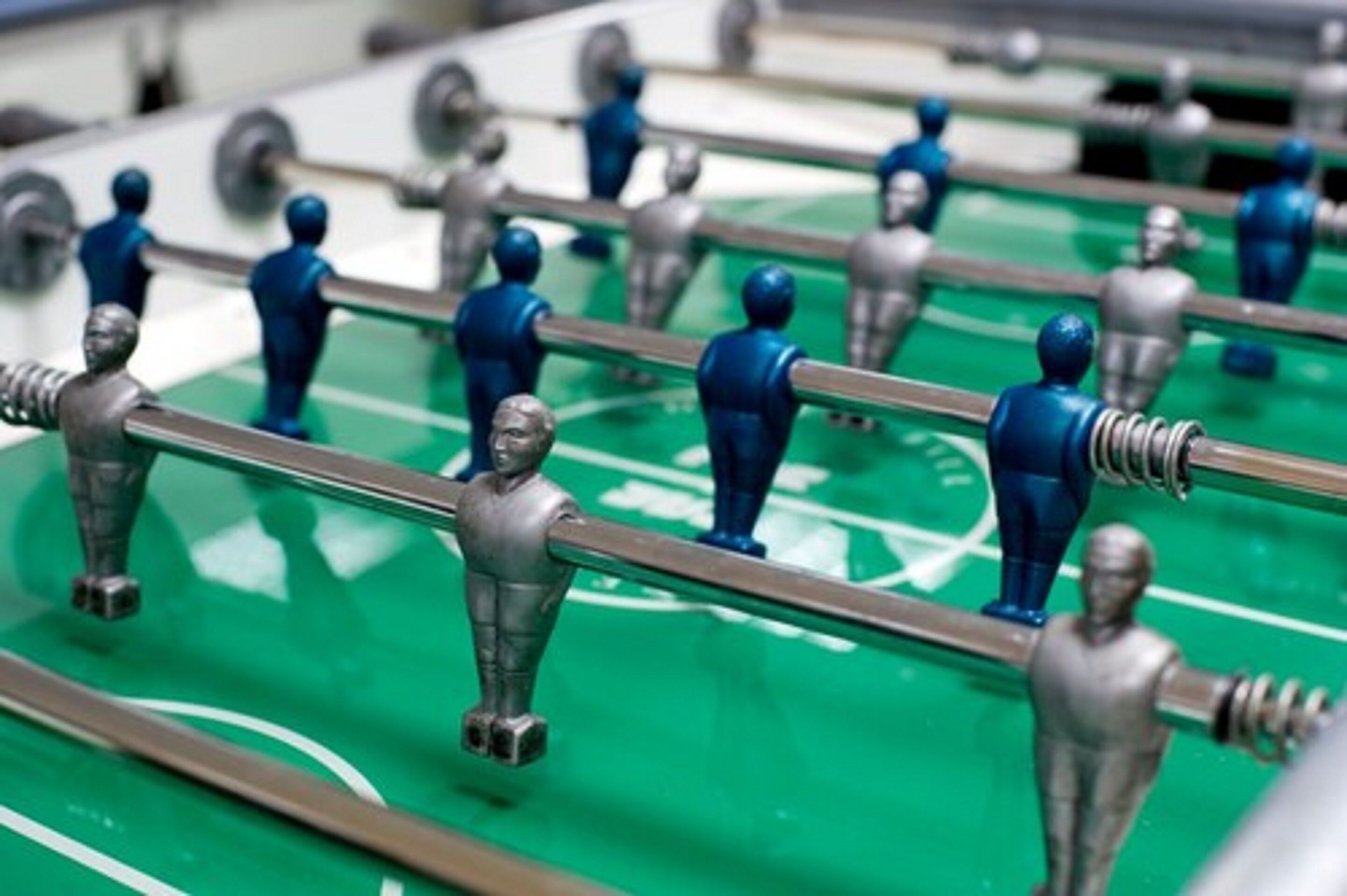 A close-up of a foosball table with metallic figures and rods.