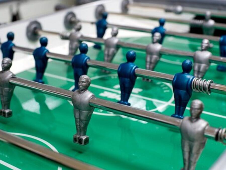 A close-up of a foosball table with metallic figures and rods.