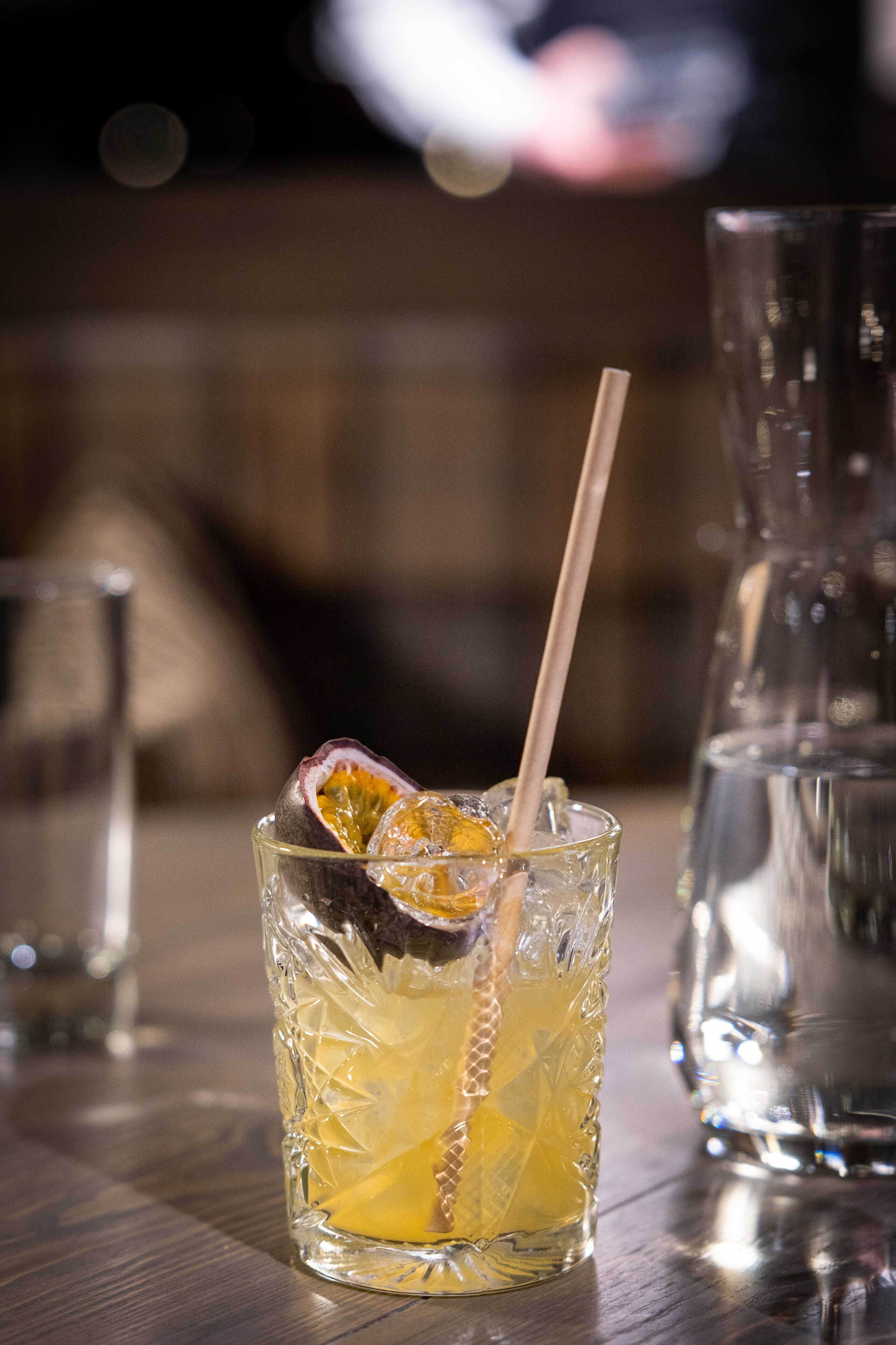 A glass with a straw, containing a beverage and a slice of fruit, placed on a table.