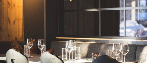 Een restaurantinterieur met een houten wand, grote hanglampen en uitzicht door een raam.