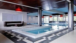 A modern indoor pool area with a checkered floor, large windows, and red accents. - Bardøla Fjelltun (Hol)