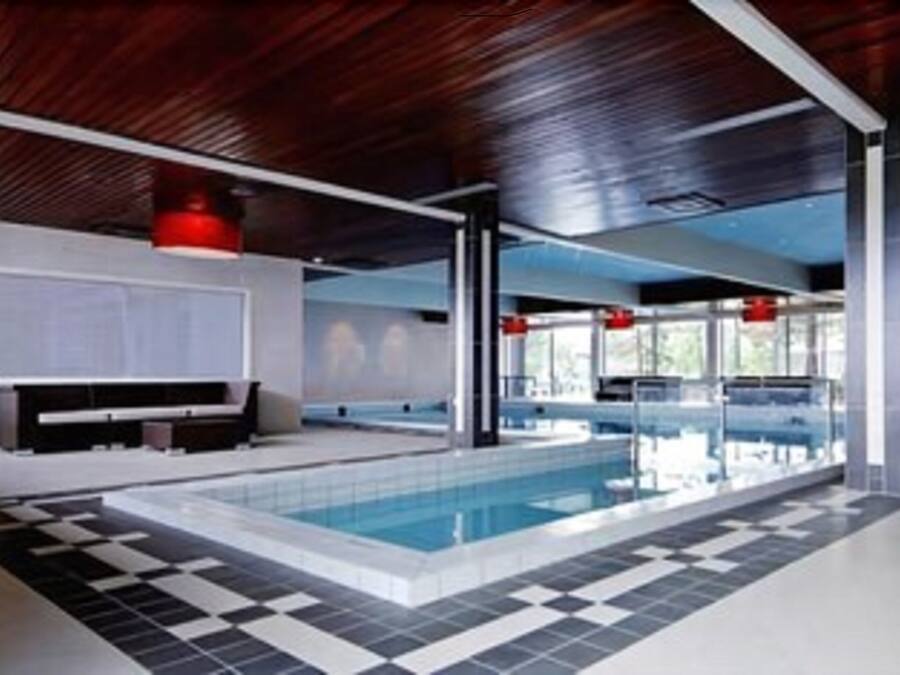 A modern indoor pool area with a checkered floor, large windows, and red accents.