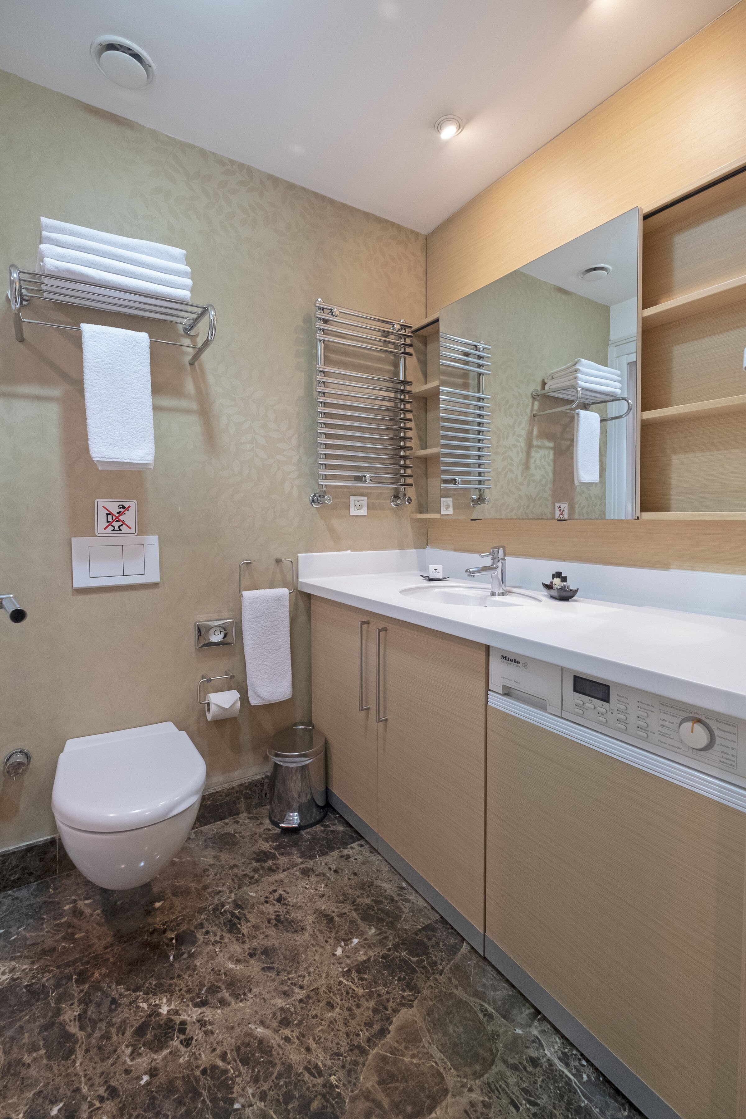 Een moderne badkamer met toilet, wastafel en handdoekhouders.