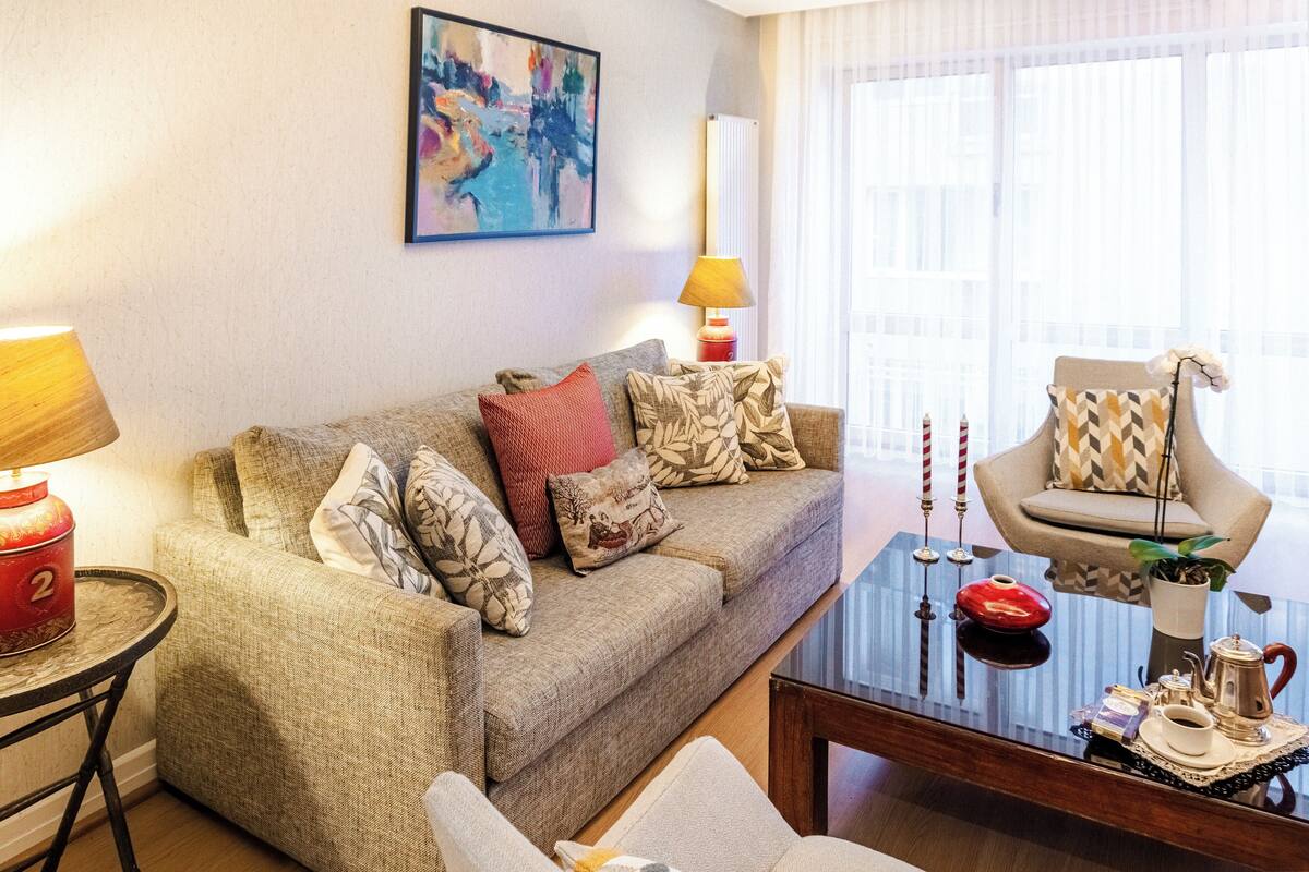 Una sala de estar con sofá, sillón, mesa de centro y lámpara.
