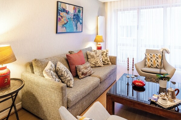 A living room with a sofa, armchair, coffee table, and a lamp. - Cheya Residences Nisantasi Deluxe (Istanbul)
